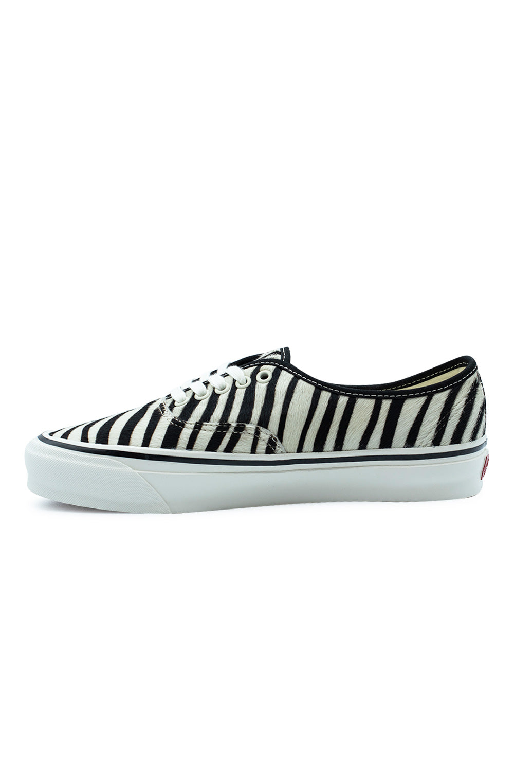 Medial side profile view of the Vans LX Authentic 44 shoe in Zebra Marshmallow, illustrating the dense vertical zebra stripe pony hair pattern, clean black collar binding, and thick vulcanized rubber sole with classic textured toe bumper.