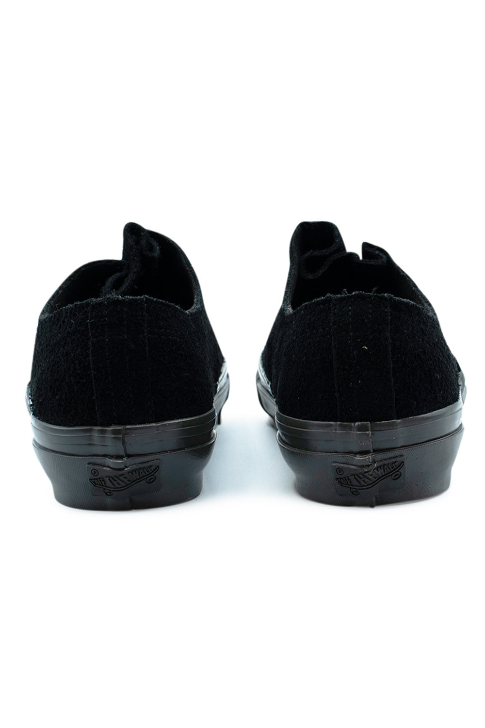 Rear view of the heels of the Vans LX Authentic Ease Black / Faded Black shoes, featuring the raw-edge hairy suede heel seam, glossy faded black foxing tape, and a tonal black Off The Wall rubber heel license plate patch.