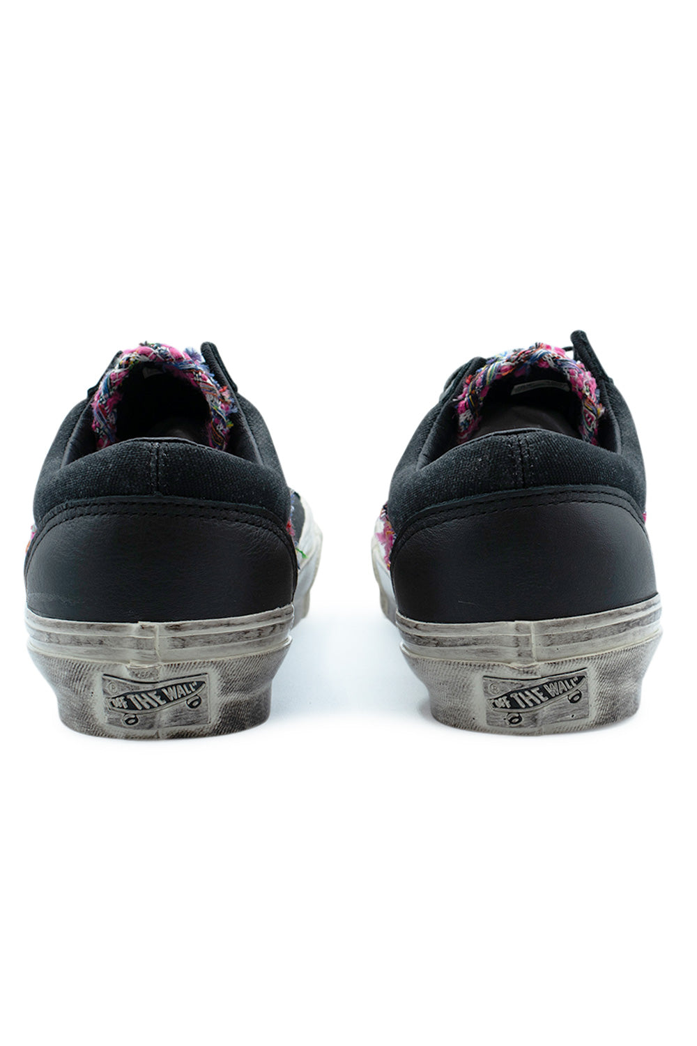 Rear view of the heels of the Vans LX Old Skool 36 Souvenir shoes, displaying the washed black full-grain leather heel overlays, distressed worn foxing tape, and a faded vintage Off The Wall heel license plate badge.