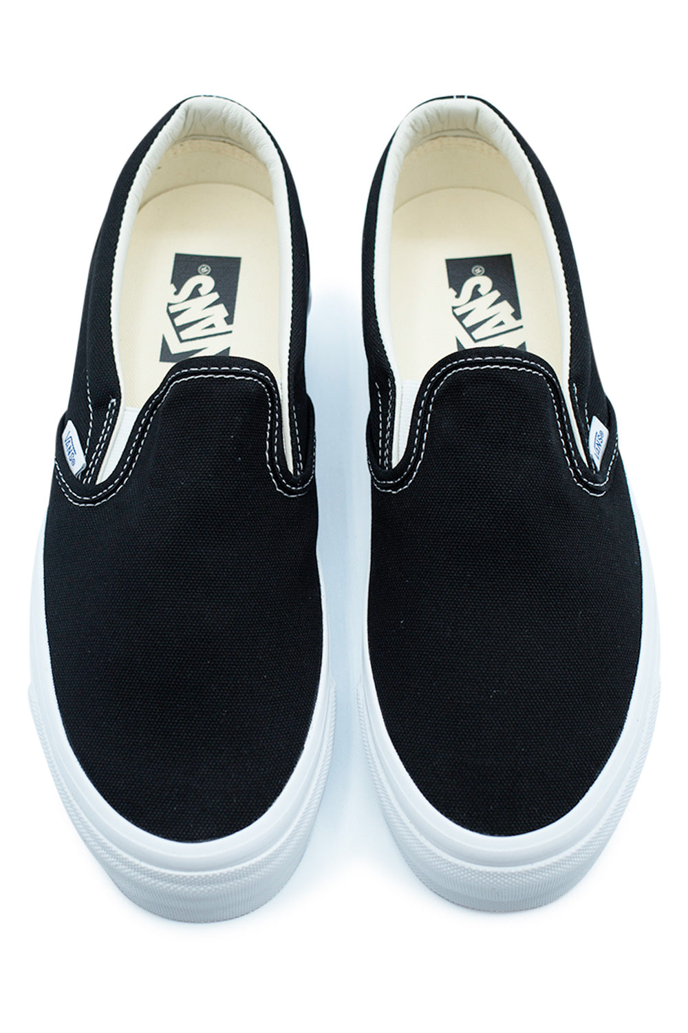 Top view of Vans LX Slip-On Reissue 98 Black / White showing minimalist slip-on design, durable black canvas upper, padded collar and Vans ADC comfort insole