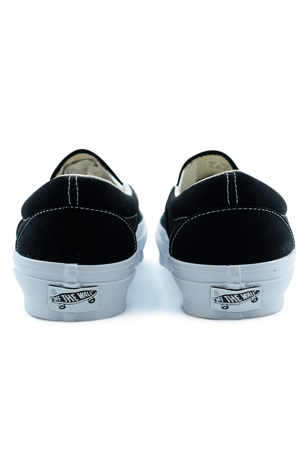 Rear view of Vans LX Slip-On Reissue 98 Black White with Off The Wall heel badge, vintage skate shoe construction and elevated glossy foxing sidewall