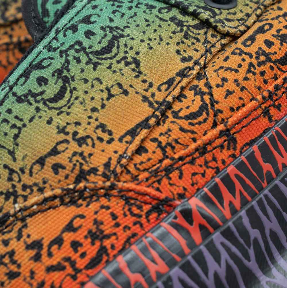 Extreme macro close-up of the canvas weave on the Vans OTW x Chito Half Cab 33, showing the smooth color fade from neon green to warm orange, heavy-duty double stitching, detailed black screen-printed skull linework, and the upper border of the red-accented rubber foxing stripe.