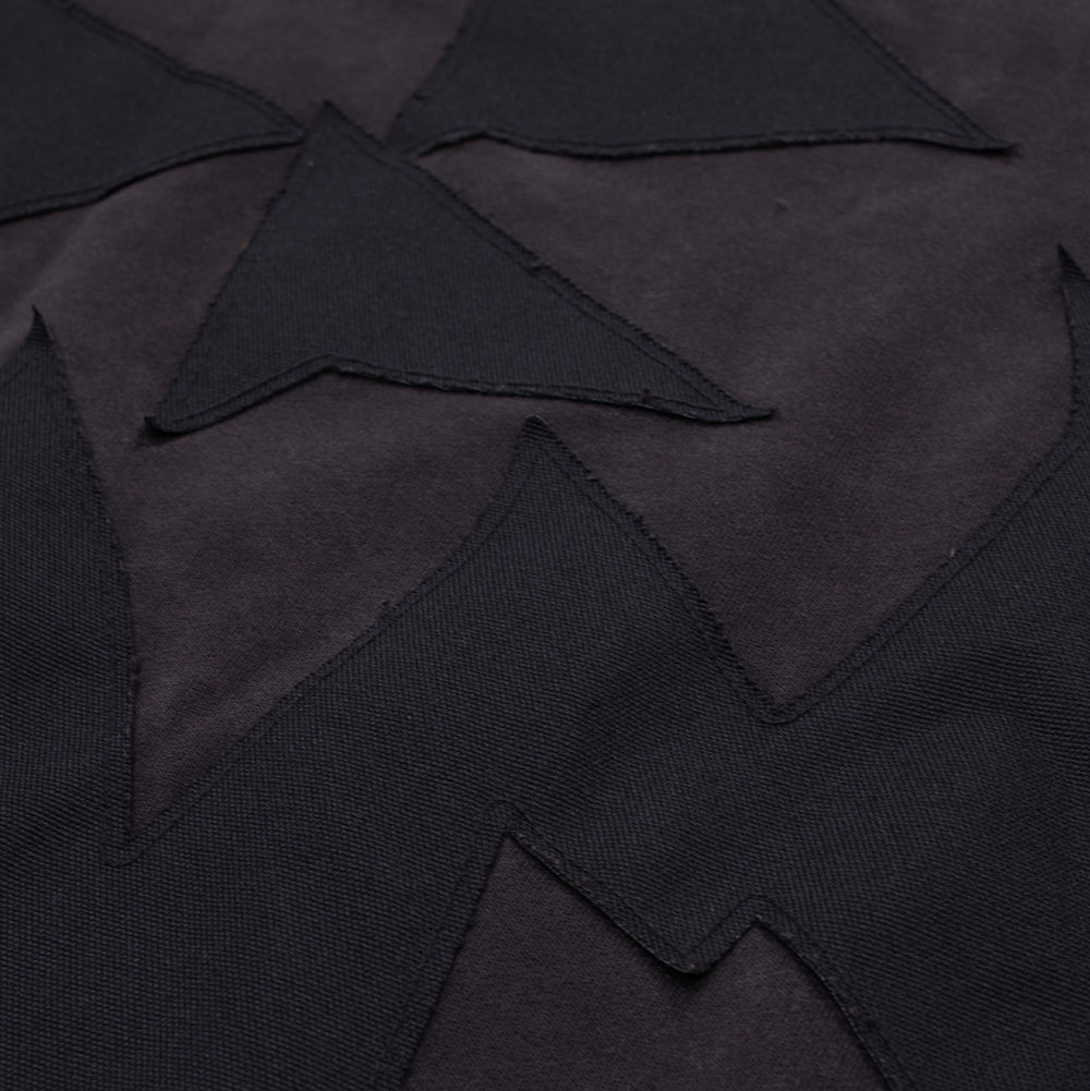 Detailed macro texture shot of the rear applique on the Vans OTW x Chito Sweatshirt, highlighting the raw-cut twill fabric edges, precision zig-zag perimeter stitching, and geometric angular facets set against the sun-faded black sweatshirt body.