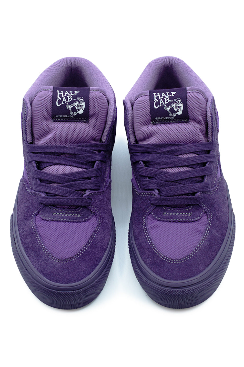 Top-down view of a pair of Vans Skate Half Cab shoes in Purple Licorice, highlighting the breathable purple mesh toe box inserts, durable suede ollie overlays, tonal purple laces, and padded mesh tongues with woven black and white Half Cab Steve Caballero logo patches.