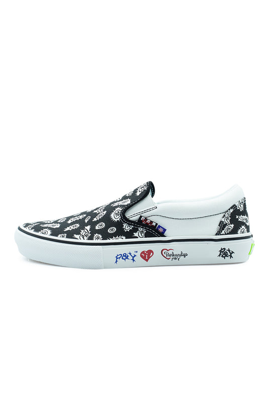 Lateral side profile of the Vans X Punk And Yo Skate Slip-On shoe in Black and White, showcasing heavy-duty canvas uppers covered in a custom spiked bandana paisley print, solid white canvas collar quarter panels, elastic side gussets, textured white rubber foxing tape with printed blue and red Punk and Yo logos, a black foxing stripe, and a neon green heel scab label