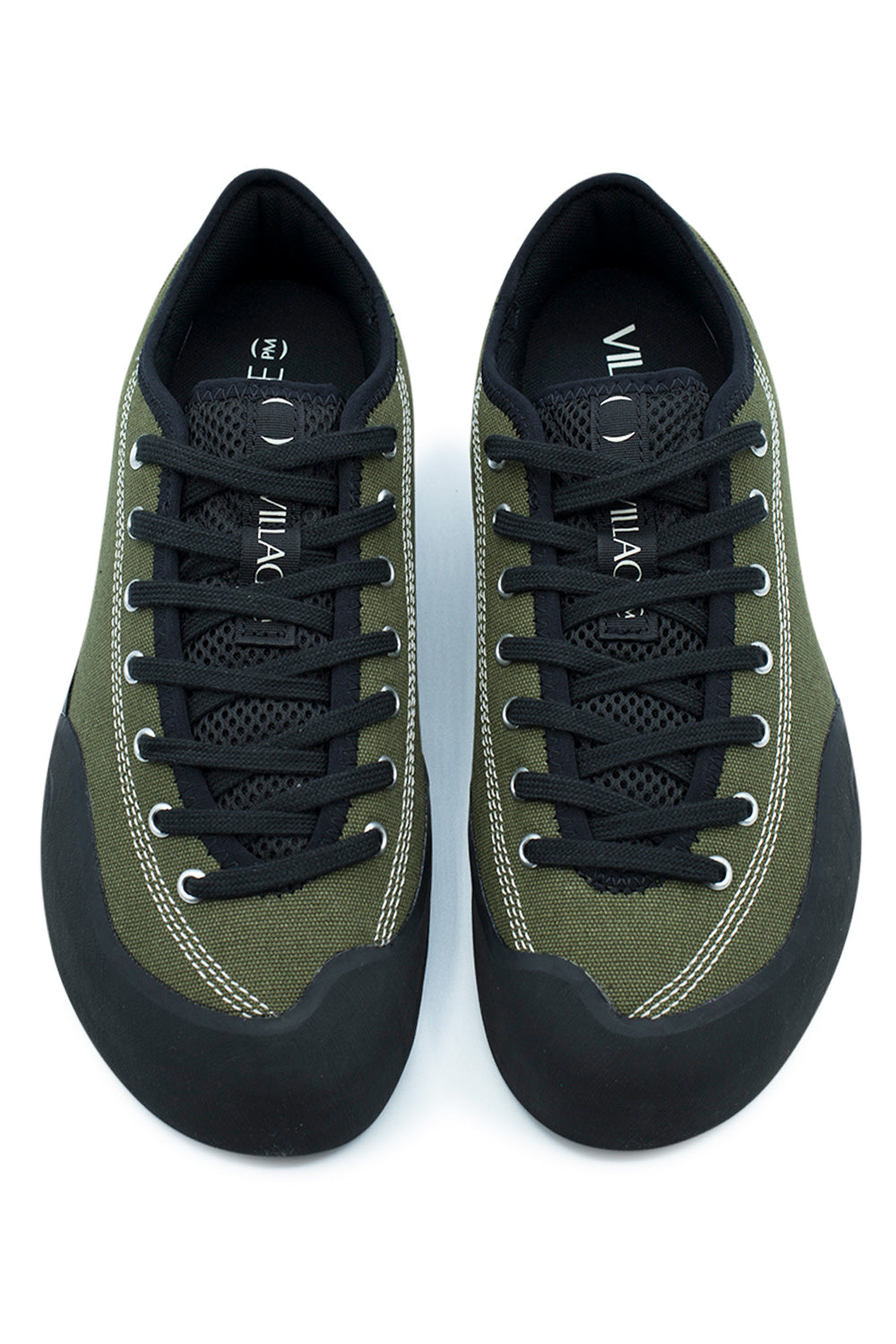 Top-down view of a pair of Village PM 1.30PM skate shoes, highlighting the anatomical asymmetrical foot shape, protective wrapped matte black climbing rubber toe caps, extended toe-to-collar black lacing system through silver eyelets, breathable black open-mesh tongues, and black branded pull loops with white "VILLAGE" block lettering.