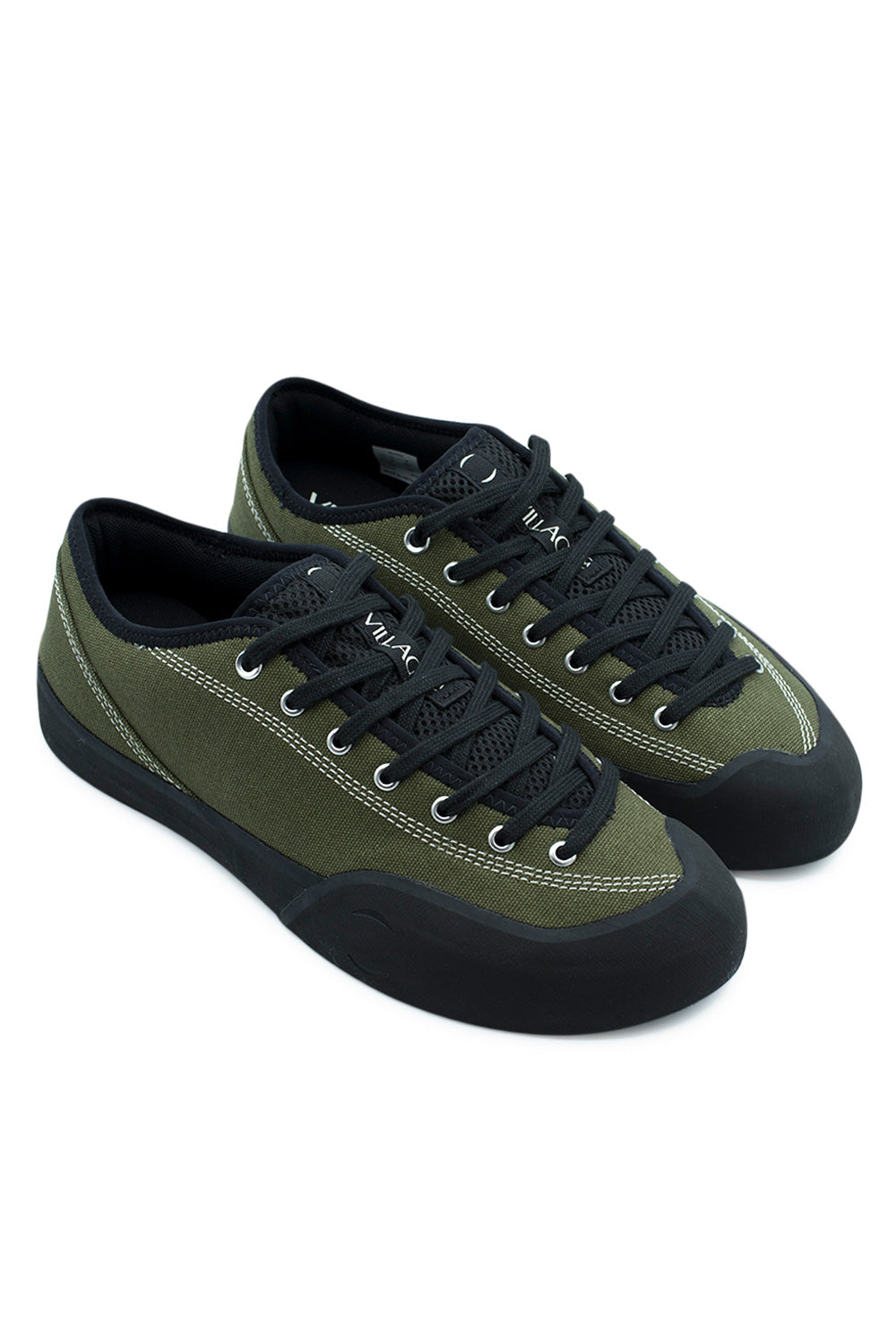Elevated three-quarter studio perspective of the Village PM 1.30PM in Olive and Natural Black, detailing the hybrid combination of outdoor rock climbing approach footwear and skateboard shoe design, featuring an asymmetrical low-profile canvas upper and high-coverage black rubber foxing.