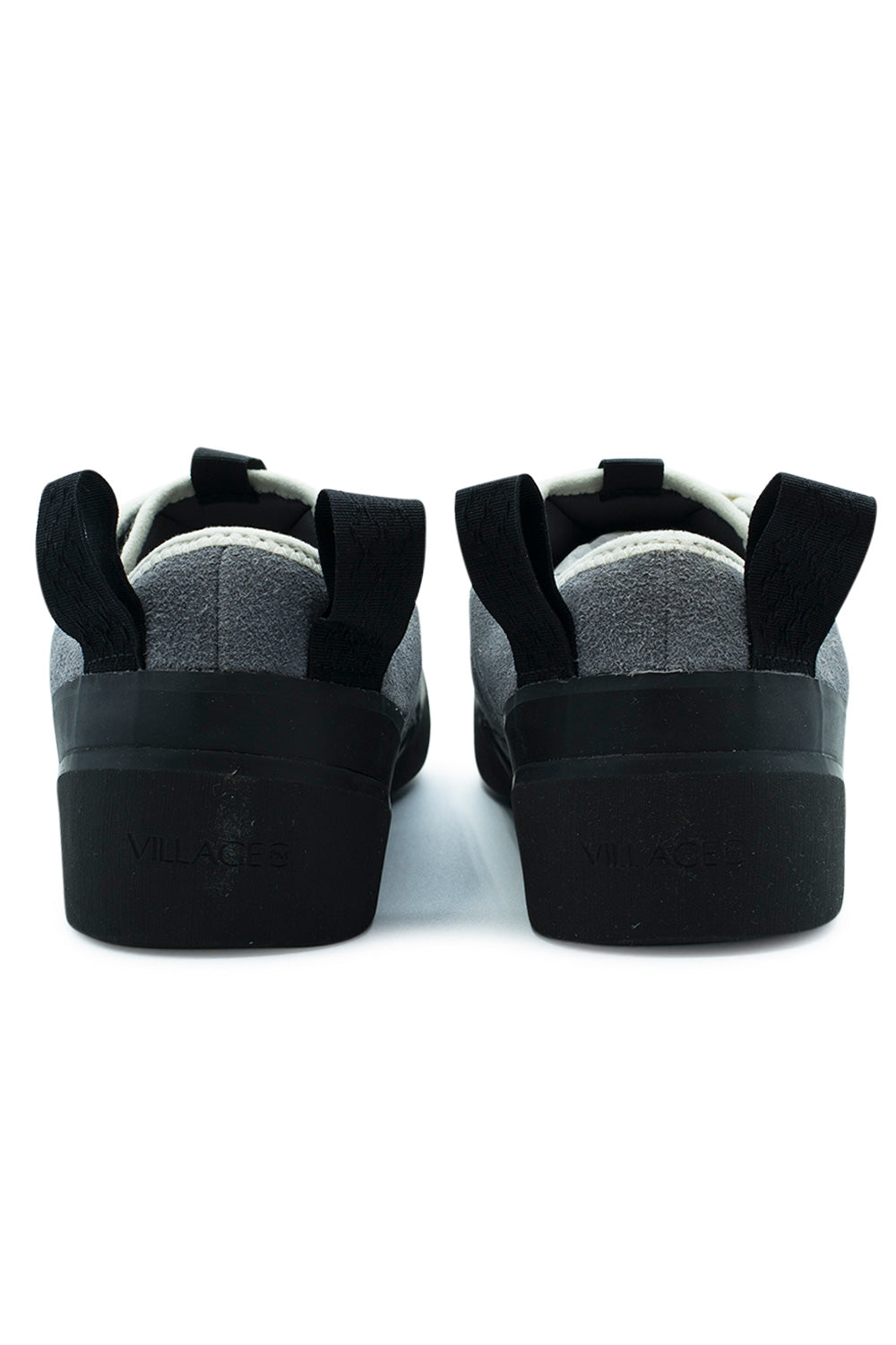 Rear perspective shot of the heels of the Village PM 1PM sneakers, displaying the dual wide black woven pull loops, light grey suede upper heel seam, padded off-white collar piping, and high-walled black rubber heel foxing embossed with subtle "VILLAGE" block lettering[cite: 91].