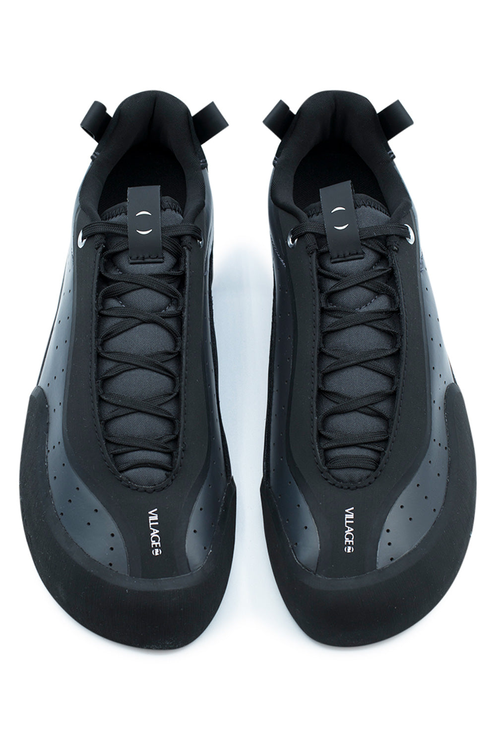 Top-down view of a pair of Village PM 2PM Anthracite skate shoes, showcasing the anatomical asymmetrical shape with angular toe box, protective matte black climbing rubber toe bumpers, extended black lacing tucked beneath protective rubber eyestay shields, perforated side panels, and branded tongue pull tabs printed with white "VILLAGE" logos.