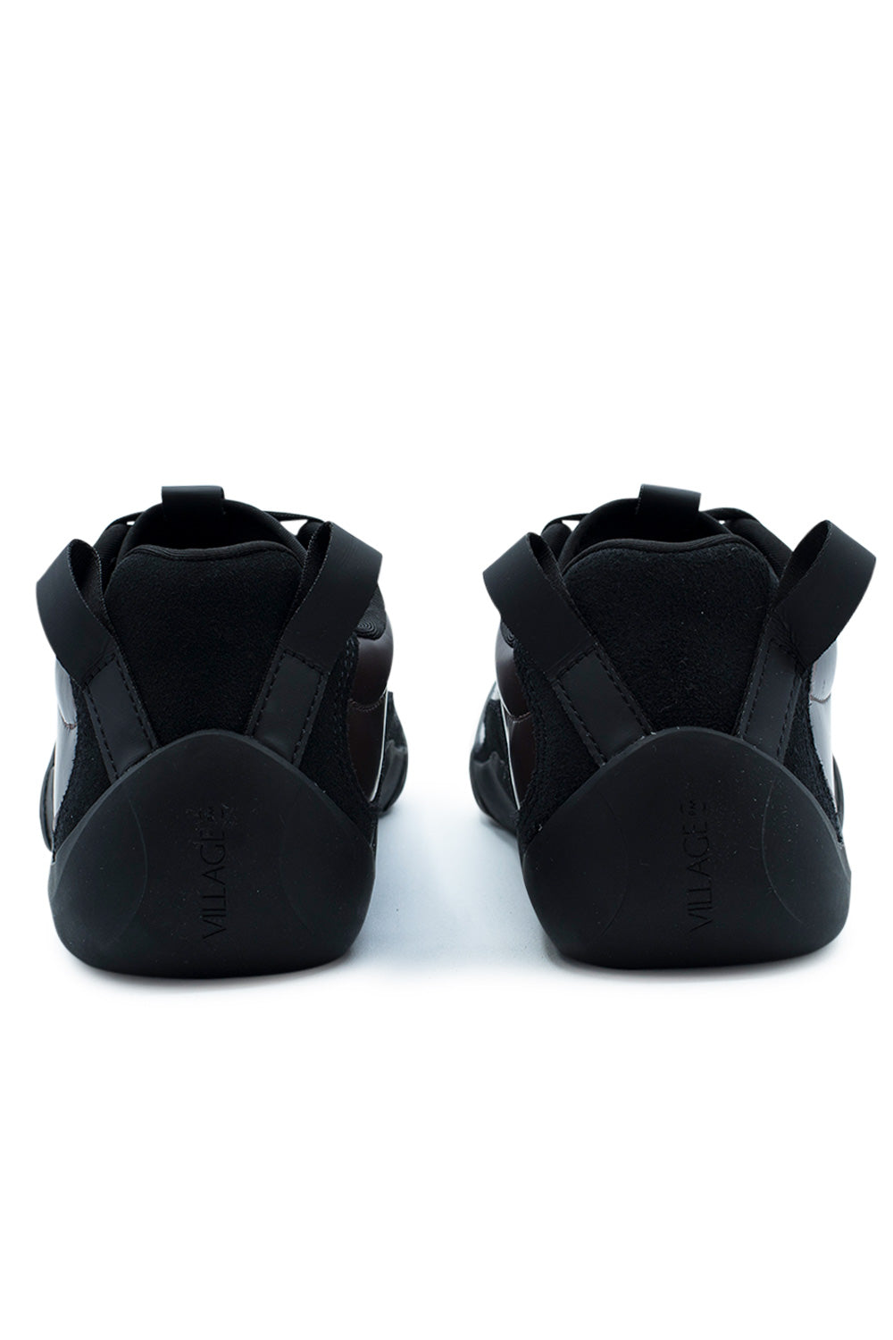 Rear studio shot of the heels of the Village PM 2PM sneakers, displaying the high-wrapped natural black climbing rubber heel counter embossed with vertical "VILLAGE" lettering, padded black textile collar, and twin heavy-duty black webbing pull loops angled outward.