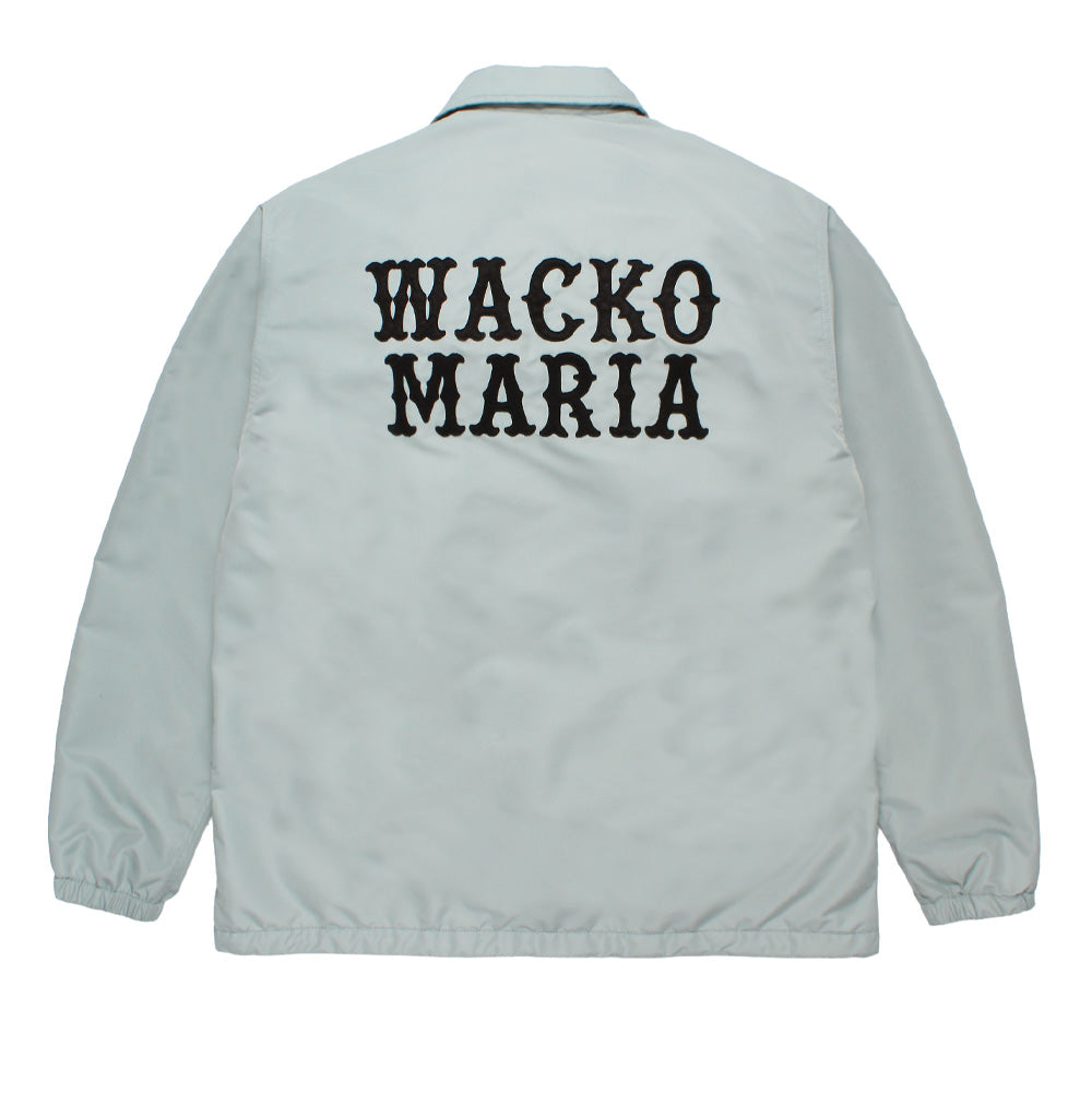 Back studio view of the Wacko Maria Coach Jacket Type 2 in light grey, showcasing a relaxed streetwear silhouette with a pointed turn-down collar, elasticated cuffs, straight hemline, and prominent two-tier stitched black felt applique letters spelling out "WACKO MARIA" across the upper back.