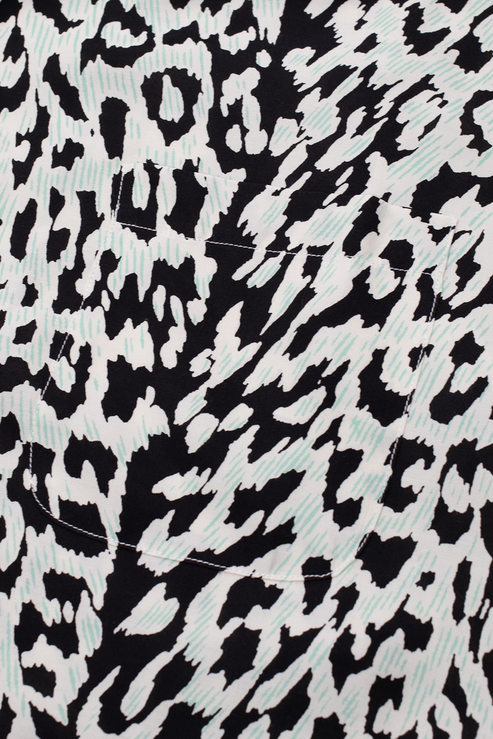Detailed shot of the left chest pocket on the ivory Wacko Maria shirt, displaying how the black and mint animal print pattern seamlessly aligns with the main body.