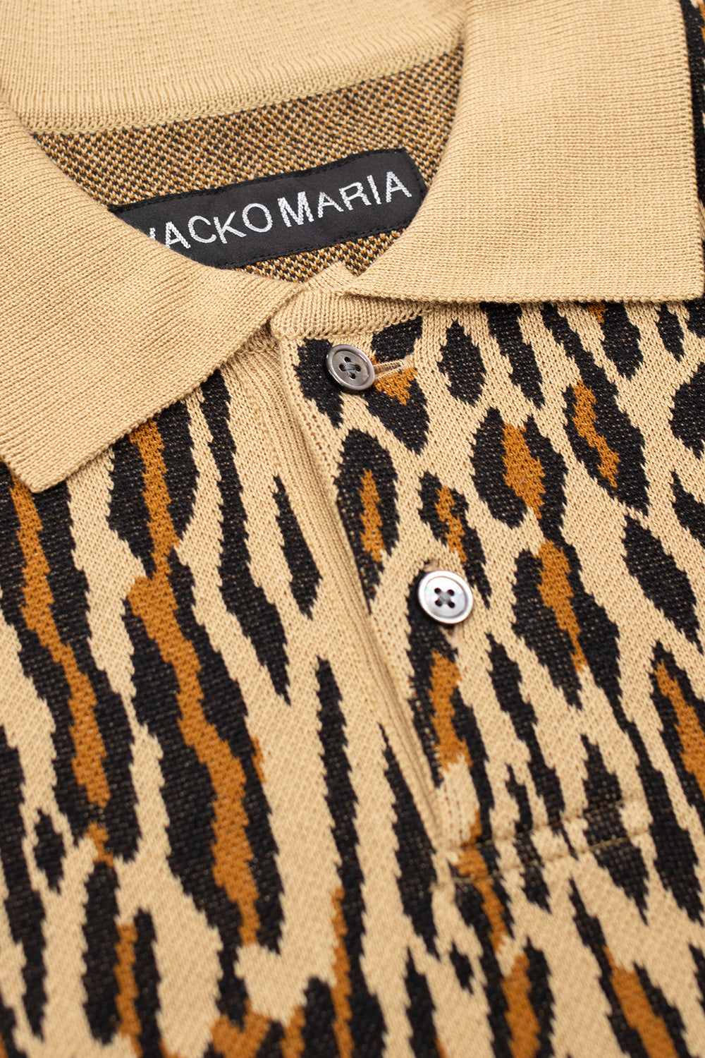 close up of Wacko Maria knit polo collar and button placket, featuring beige leopard pattern, mother-of-pearl buttons and high quality cotton knit construction from Japan
