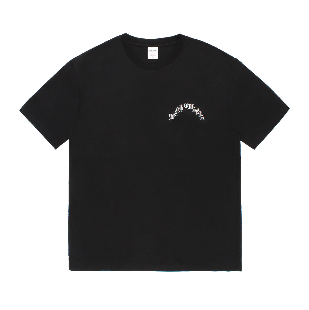 Front flat lay view of the black Wacko Maria Washed Heavyweight T-Shirt Type 4, showcasing the relaxed drop-shoulder cut, seamless tubular knit torso, white woven inner neckline tag, and an arched white Old English gothic "WACKO MARIA" screen-printed logo positioned across the left chest.