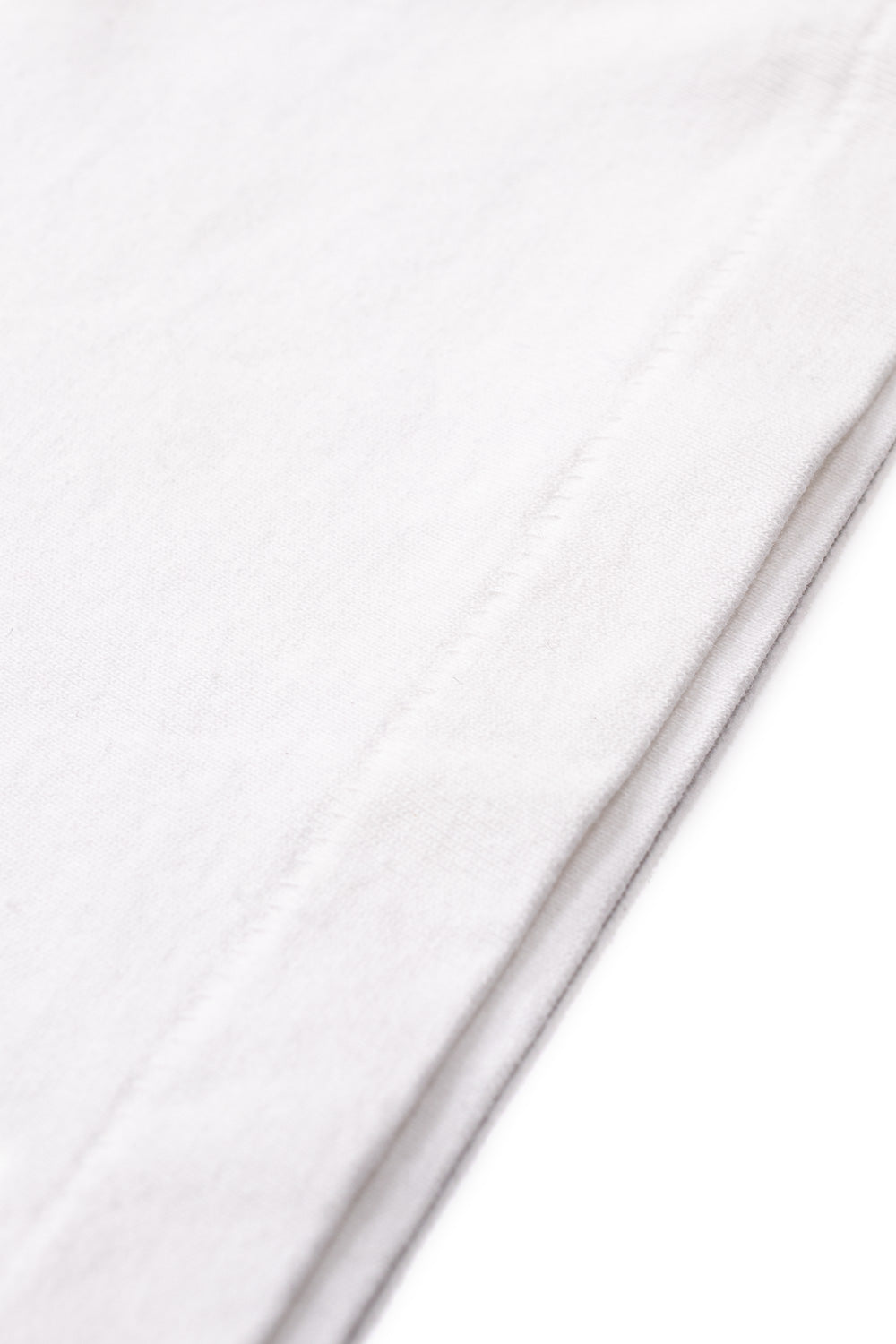 Detailed view of the premium quality vintage single-stitch hem on the white Wacko Maria washed heavy weight cotton t-shirt.