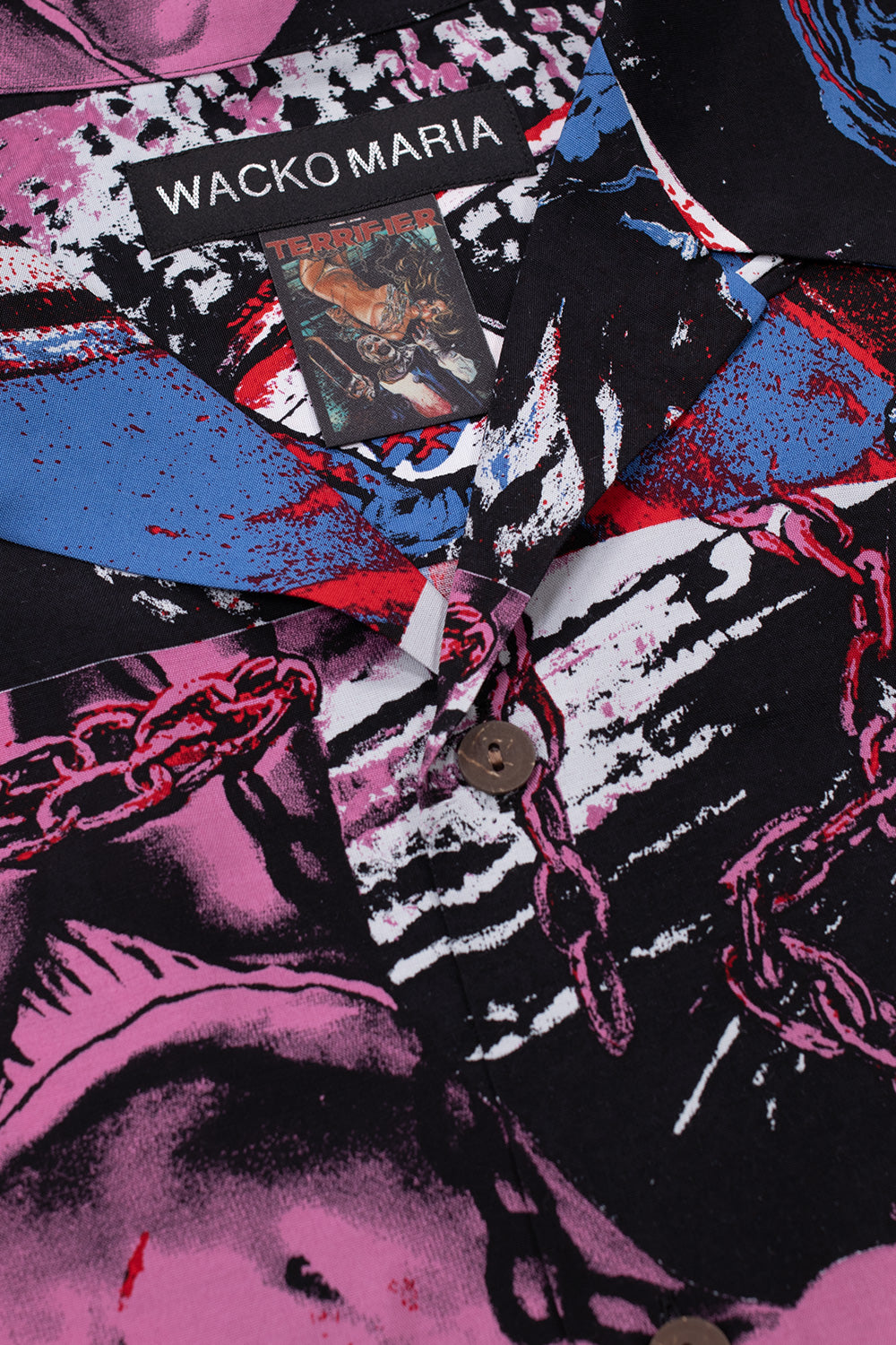 Close-up of Wacko Maria x Terrifier shirt collar with woven brand label and Terrifier movie tag, lightweight rayon fabric, vibrant all-over graphic print with button-up front