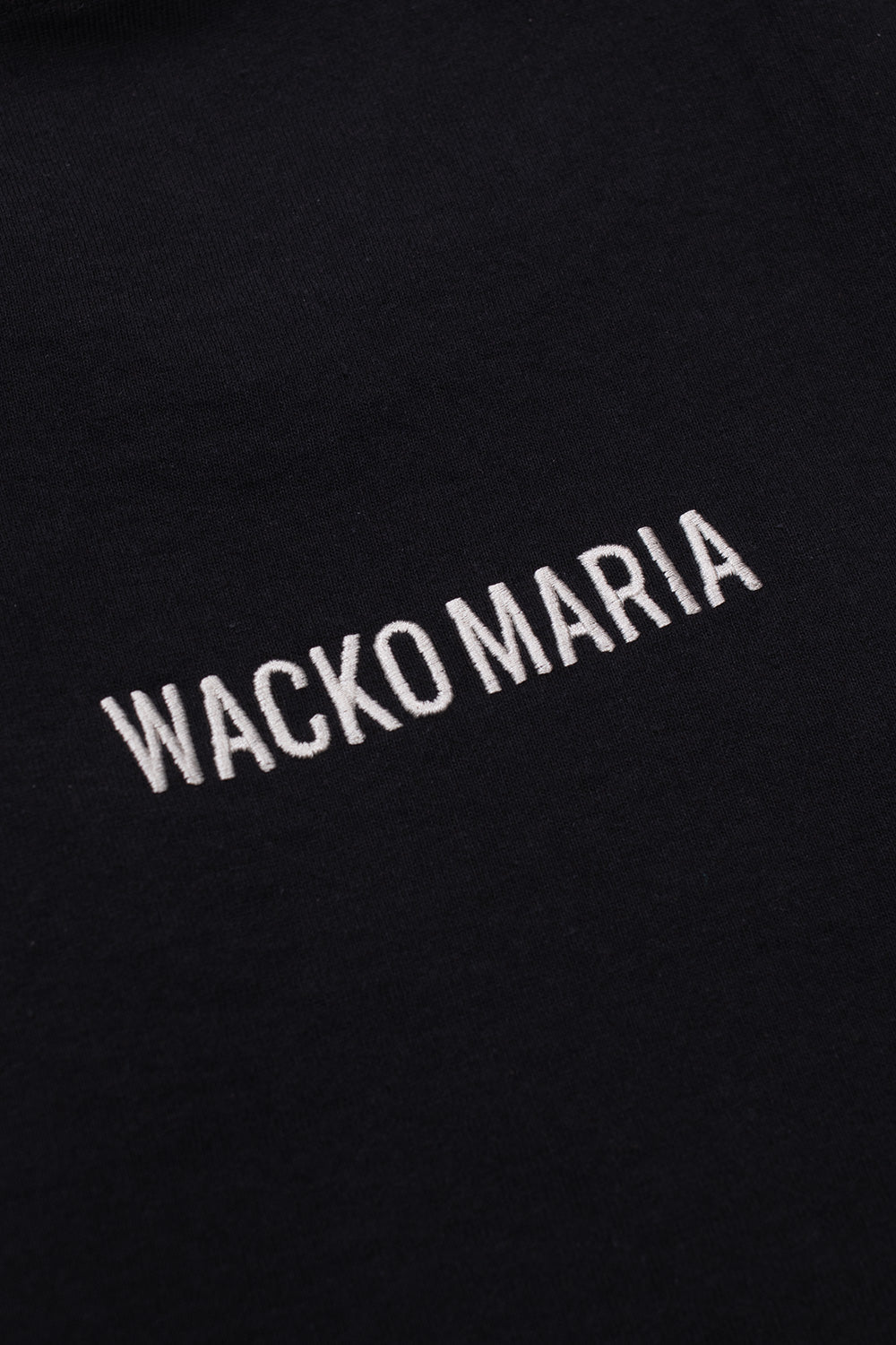 Detailed shot of Wacko Maria embroidered lettering on back of washed black T-shirt, luxury Japanese streetwear collaboration with Terrifier film franchise