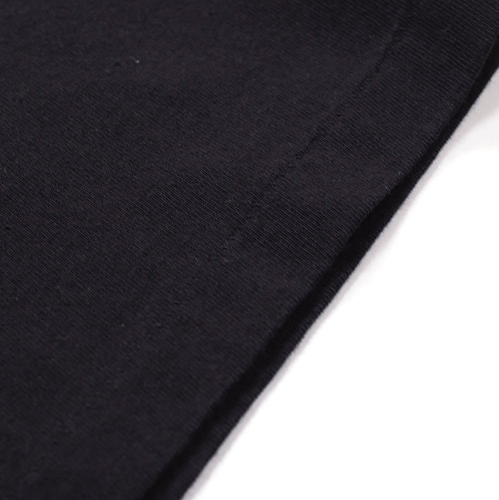 Extreme macro close-up of the bottom hem on the Wacko Maria x True Romance T-Shirt, highlighting the dense weave, subtle washed vintage patina, and double-needle tonal reinforcement stitching of the premium heavyweight cotton knit.