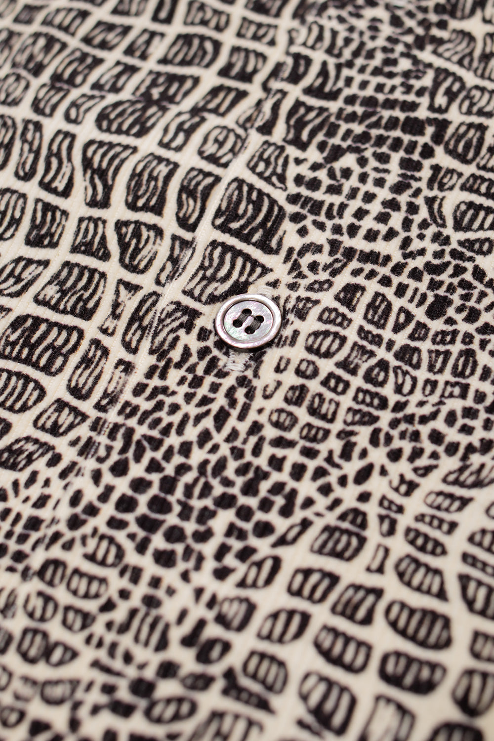 macro detail of Wacko Maria 50s shirt Type-2 featuring mother-of-pearl button, textured corduroy cotton fabric and intricate vintage inspired print, luxury Japanese craftsmanship clothing